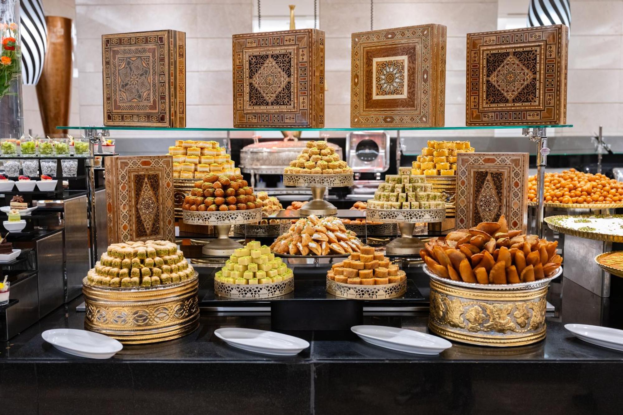 Swissotel Makkah Mecca Exterior photo The photo features a beautifully arranged display of various desserts and pastries. The setup includes multiple trays and decorative containers showcasing different types of sweets, likely from Middle Eastern or regional cuisines. These treats includ