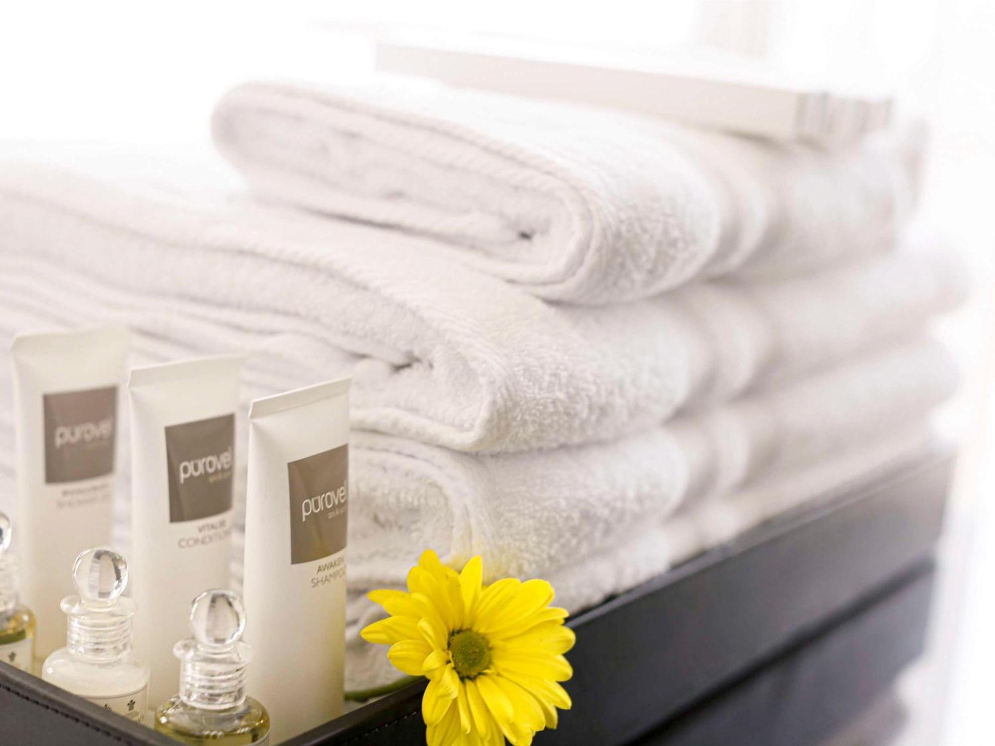 Swissotel Makkah Mecca Exterior photo The photo shows a neatly arranged stack of fluffy white towels, which are neatly placed in a basket. In front of the towels, there are several small bottles of skincare products or toiletries, likely from a brand named "pure." Additionally, there's a