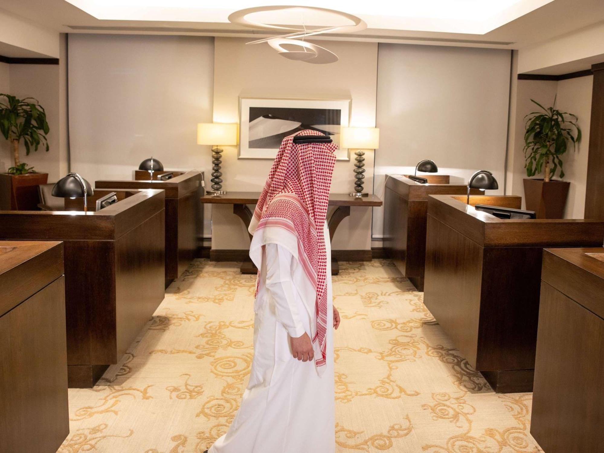 Swissotel Makkah Mecca Exterior photo The photo shows a man dressed in traditional attire, including a white thobe and a red-and-white checkered headscarf, walking through a modern office space. The office features wooden furniture, including desks and decorative lamps, creating a profes